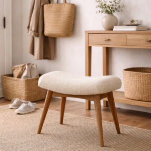 Upholstered boucle hallway stool with wooden legs styled in a modern entryway, placed on a natural rug beside shoe storage and wall hooks.