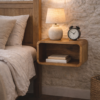 Floating solid mango wood bedside shelf styled in a rustic bedroom next to an oak bed, featuring a ceramic lamp, classic alarm clock, and open storage below.