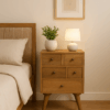 Nordic-style bedside cabinet with four drawers placed in a cozy guest bedroom, styled with a white vase, green plant, lamp, and neutral bedding.