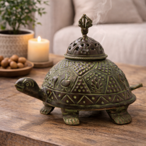 Antique turtle-shaped brass incense burner with decorative patterns, placed on a wooden coffee table in a cosy living room with candlelight and a plant in the background.