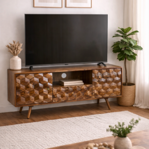 Solid mango wood media unit with geometric carved doors and open shelving, styled in a modern neutral living room with TV, indoor plant, and soft furnishings.