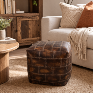 Brown patchwork leather pouffe with stitched panel design styled in a warm, cosy living room with a leather sofa, plants and textured rug.